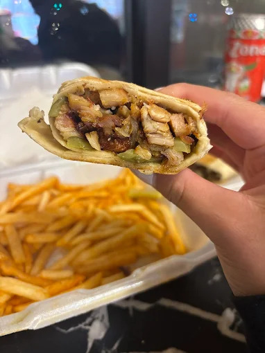 Box of sliced shawarma wraps with pickled vegetables and dipping sauces